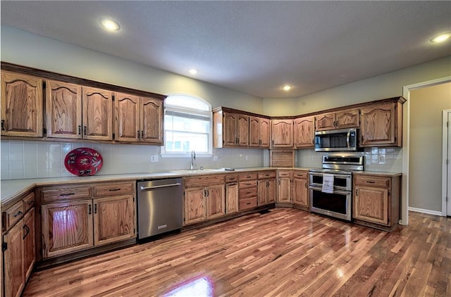 kitchen featuring stainless steel appliances, wood finished floors, a sink, and light countertops