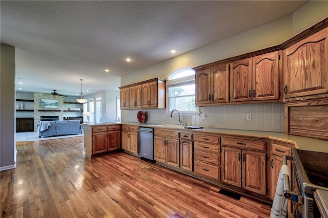 kitchen featuring dark wood-style flooring, a fireplace, decorative backsplash, brown cabinetry, and a peninsula