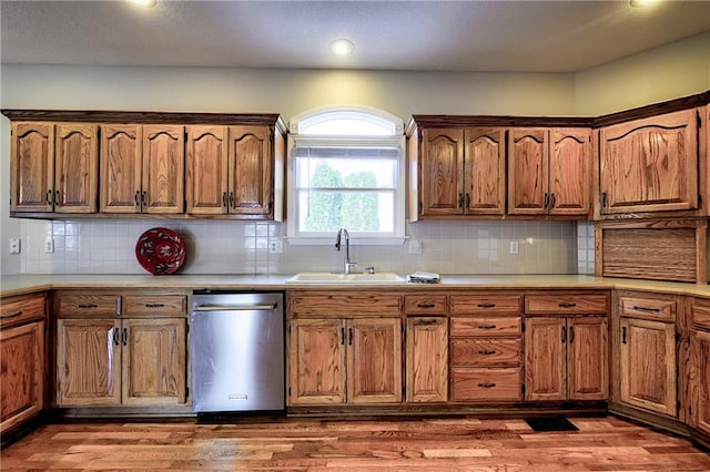 kitchen featuring dishwasher, light countertops, wood finished floors, and a sink