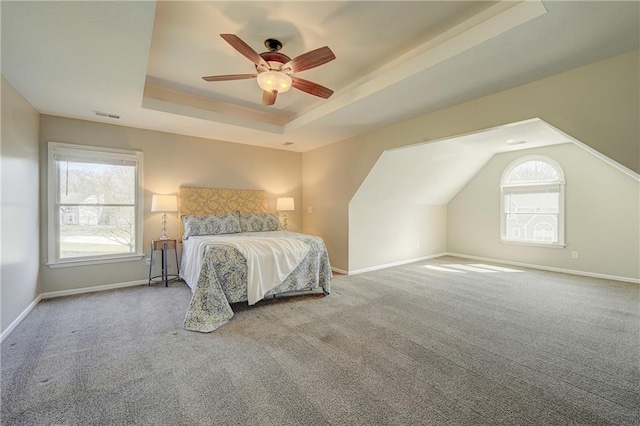 bedroom featuring carpet floors, visible vents, a tray ceiling, and baseboards