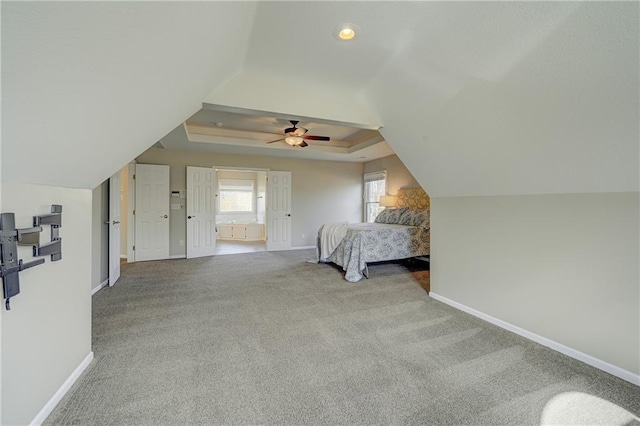 unfurnished bedroom featuring baseboards, a ceiling fan, carpet, a tray ceiling, and vaulted ceiling