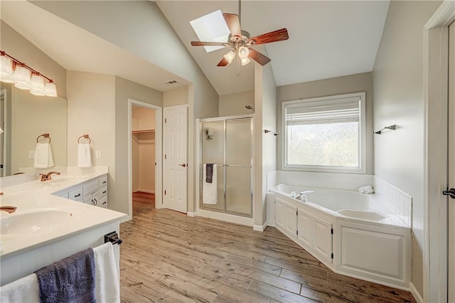 bathroom with lofted ceiling with skylight, a stall shower, vanity, wood finished floors, and a bath