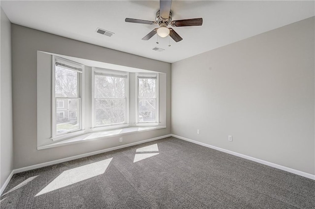 carpeted spare room with baseboards, visible vents, and a ceiling fan