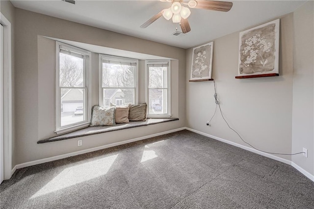 empty room with carpet floors, a ceiling fan, visible vents, and baseboards