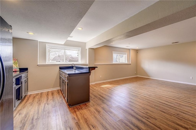 kitchen with dark countertops, light wood finished floors, baseboards, and a sink