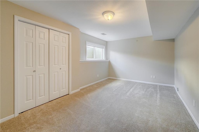 unfurnished bedroom with a closet, carpet flooring, visible vents, and baseboards