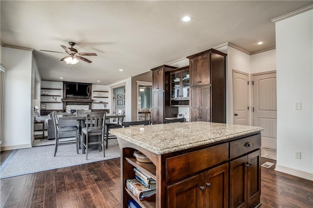 kitchen with light stone counters, dark wood finished floors, crown molding, baseboards, and ceiling fan