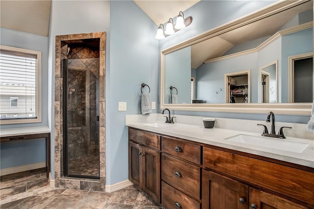 full bathroom featuring a walk in closet, double vanity, a stall shower, and a sink