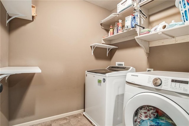 washroom with light tile patterned floors, laundry area, baseboards, and separate washer and dryer