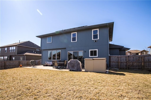 rear view of house featuring a patio, a yard, and a fenced backyard