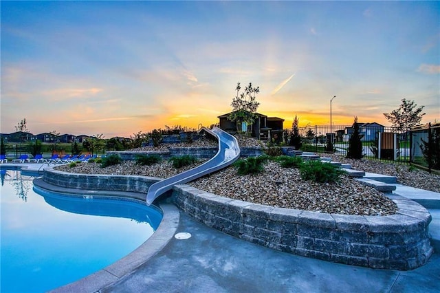 community pool with a water slide and fence