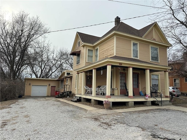 view of front of home with a garage, driveway, a chimney, and a porch