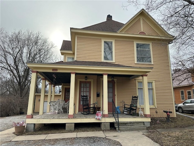 view of front of home featuring a porch, a shingled roof, and a chimney