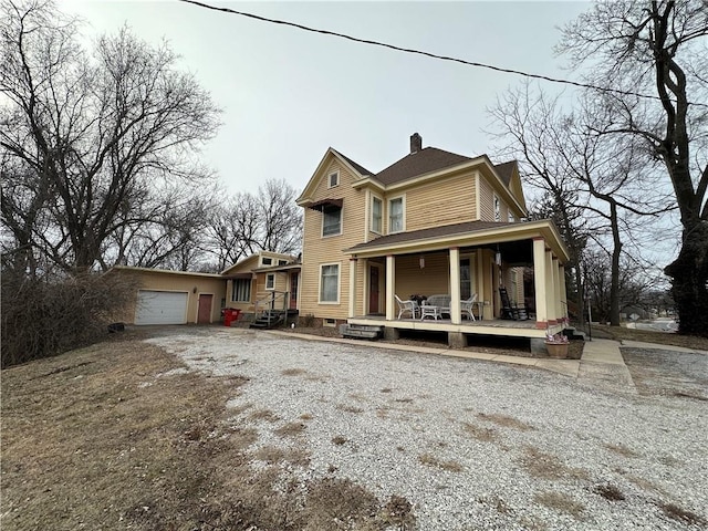 view of front facade with covered porch, driveway, a chimney, and an attached garage