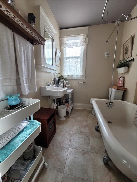 513 S Business Highway 13, Lexington, MO 64067 - bathroom featuring a freestanding bath, baseboards, a sink, and toilet