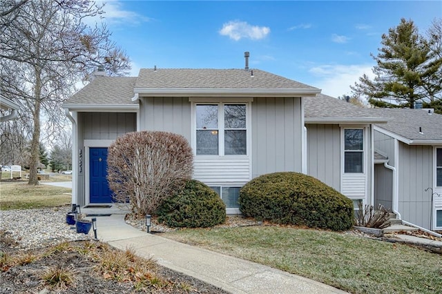 view of front of home with a shingled roof, a front yard, and a chimney