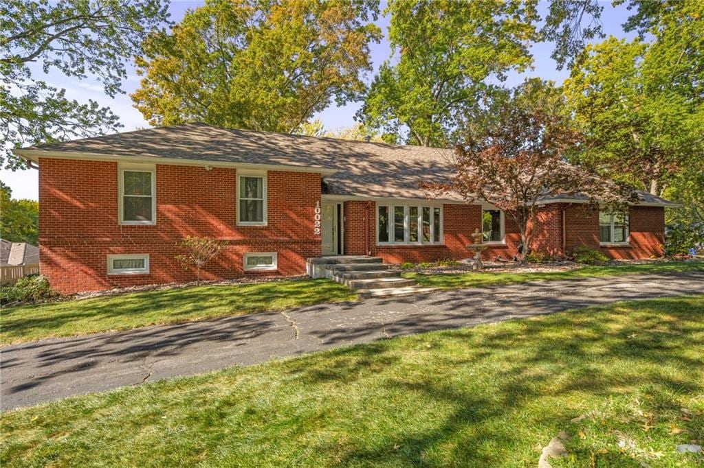 tri-level home featuring a front yard and brick siding