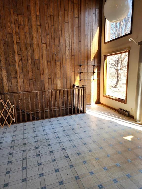11425 45th Hwy N, Platte City, MO 64079 - unfurnished living room featuring wood walls, baseboards, and a high ceiling