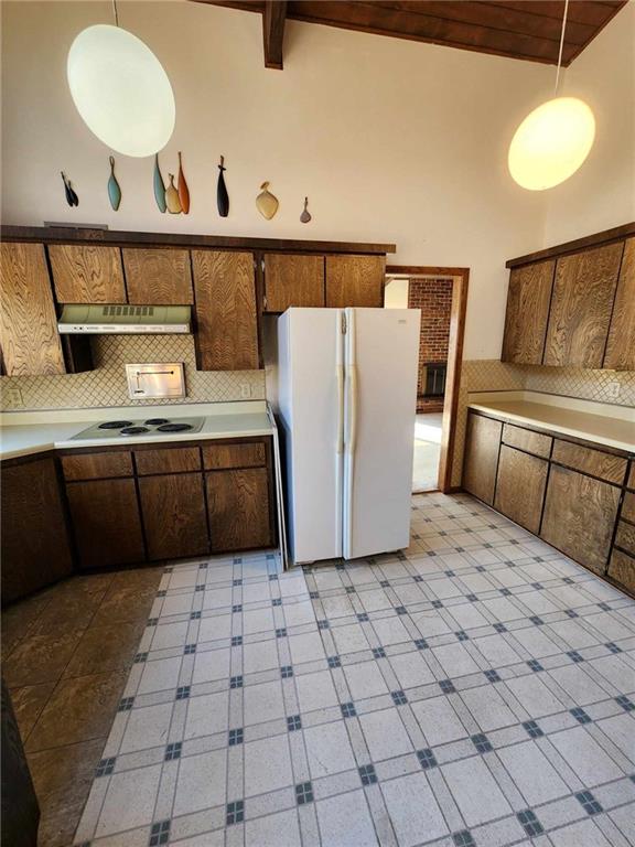 11425 45th Hwy N, Platte City, MO 64079 - kitchen with white appliances, under cabinet range hood, light countertops, backsplash, and hanging light fixtures
