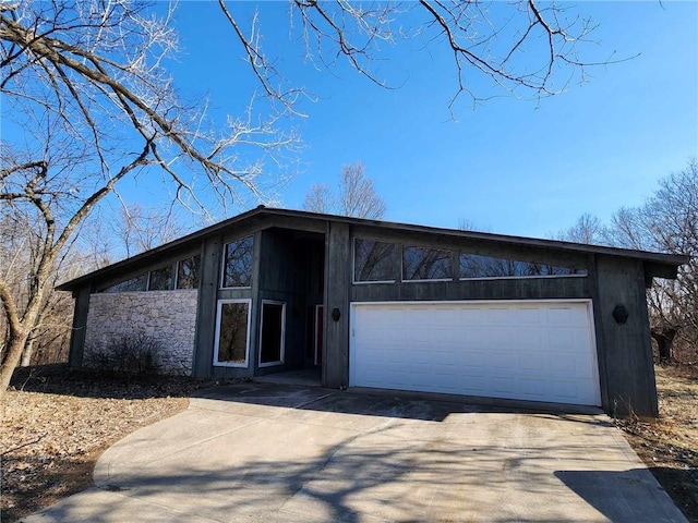 11425 45th Hwy N, Platte City, MO 64079 - mid-century inspired home featuring concrete driveway, an attached garage, and stone siding