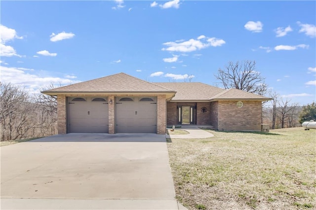 ranch-style house with roof with shingles, concrete driveway, a front yard, an attached garage, and brick siding