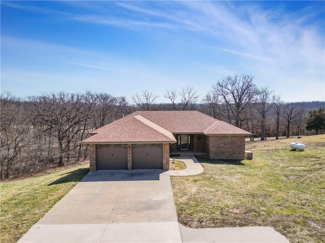 view of front facade with brick siding, an attached garage, concrete driveway, and a front yard