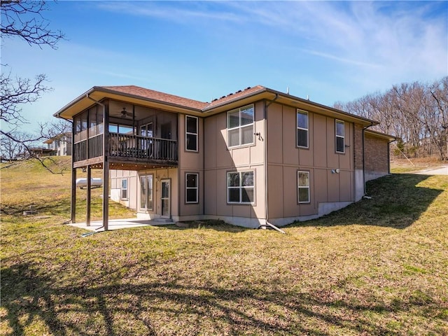 rear view of property featuring a ceiling fan, a patio area, a lawn, and a sunroom