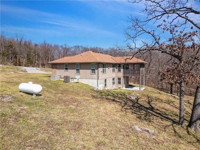 rear view of house featuring a lawn and central AC