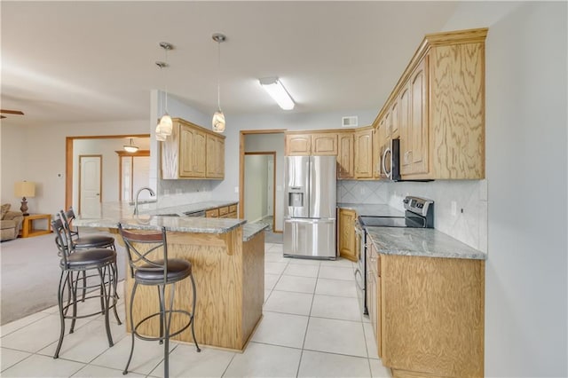 kitchen featuring a sink, a kitchen breakfast bar, stainless steel appliances, a peninsula, and light tile patterned flooring