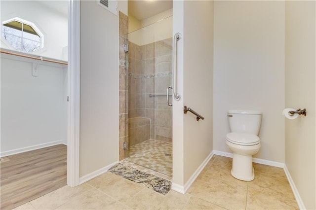 full bath with tile patterned floors, baseboards, toilet, and a stall shower