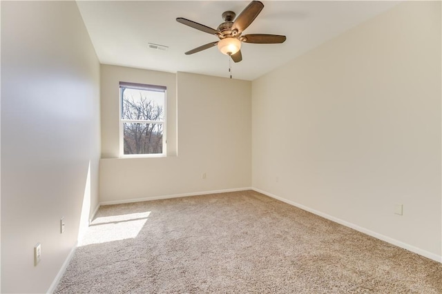 carpeted spare room featuring visible vents, baseboards, and a ceiling fan