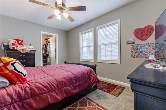 bedroom with a walk in closet, carpet floors, a closet, and ceiling fan