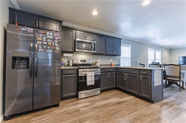 kitchen featuring crown molding, light stone counters, light wood-type flooring, appliances with stainless steel finishes, and kitchen peninsula