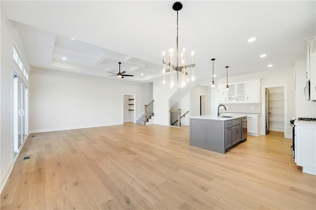 kitchen featuring gray cabinets, dishwasher, an island with sink, white cabinets, and decorative light fixtures