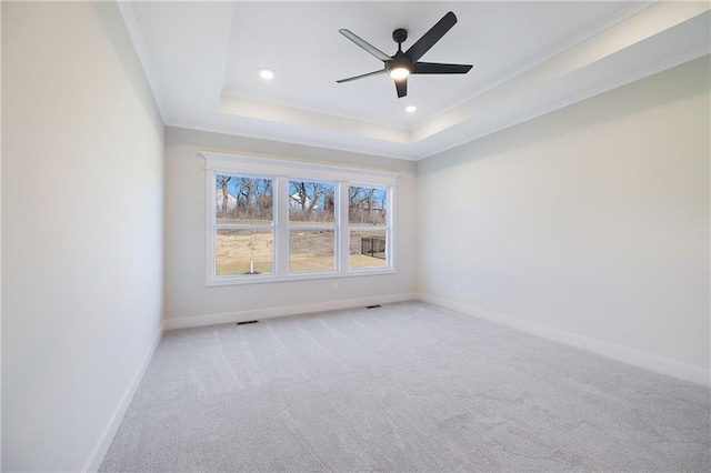 carpeted spare room featuring ornamental molding, ceiling fan, and a tray ceiling