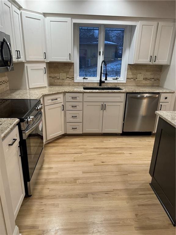 kitchen featuring stainless steel dishwasher, white cabinets, sink, and electric range