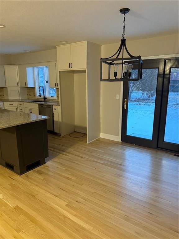 kitchen featuring white cabinetry, light hardwood / wood-style flooring, decorative light fixtures, light stone countertops, and dishwasher