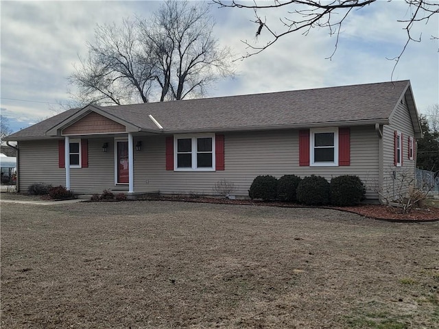 ranch-style home featuring a front yard and roof with shingles