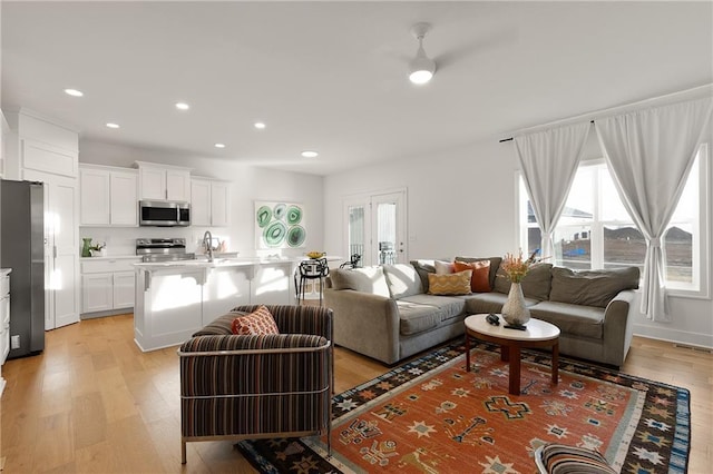 living area with visible vents, ceiling fan, light wood-style flooring, and recessed lighting