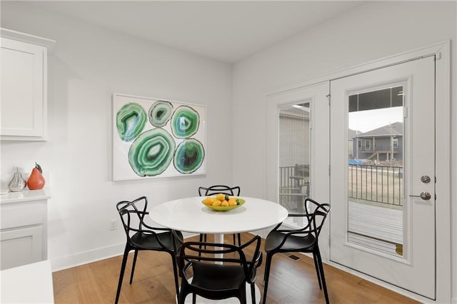 dining space with baseboards and wood finished floors