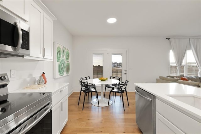 kitchen with stainless steel appliances, white cabinets, light countertops, and light wood-style flooring