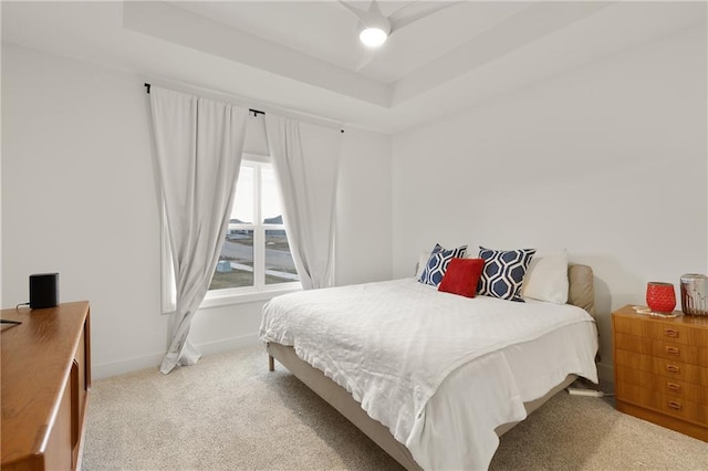 bedroom with carpet floors, a tray ceiling, and baseboards