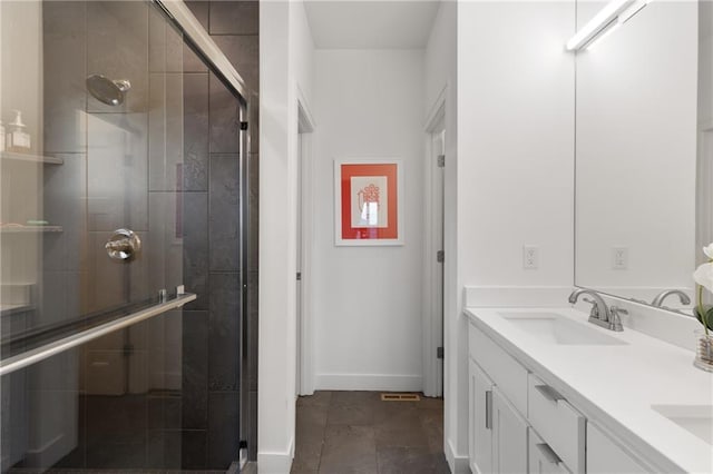 bathroom with baseboards, double vanity, a sink, and a shower stall