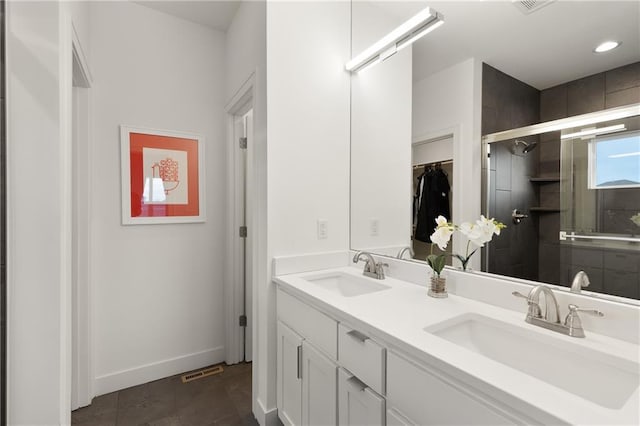 bathroom with baseboards, double vanity, a sink, and a shower stall