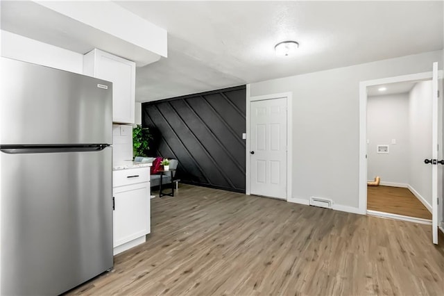 kitchen featuring white cabinets, light hardwood / wood-style floors, and stainless steel fridge