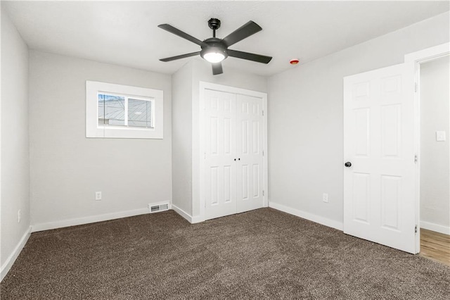 unfurnished bedroom with dark carpet, ceiling fan, and a closet