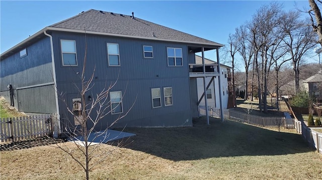 back of property with a fenced backyard, a lawn, and roof with shingles