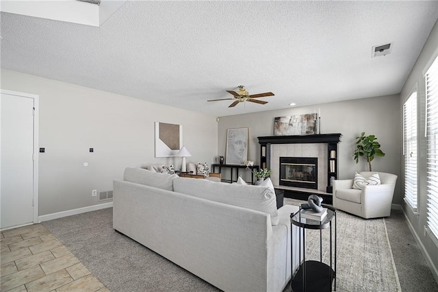 living room with ceiling fan, a fireplace, and a textured ceiling