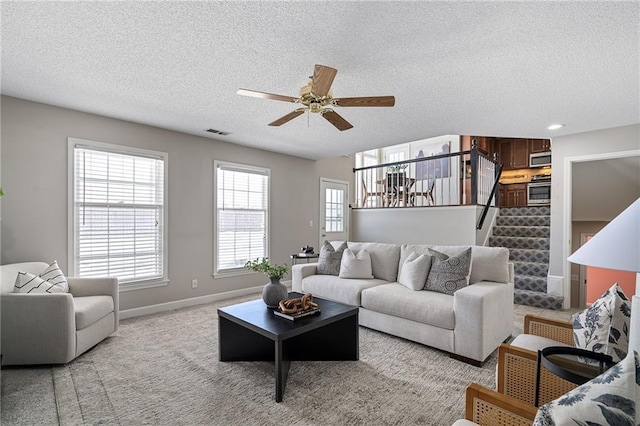 living room with ceiling fan, light colored carpet, and a textured ceiling