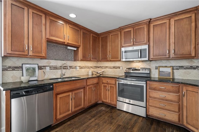 kitchen featuring sink, dark wood-type flooring, backsplash, stainless steel appliances, and dark stone counters